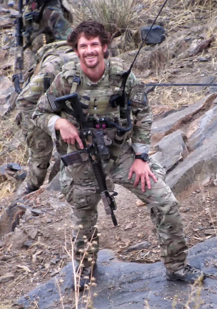 Sergeant First Class Eric Michael Emond smiling for a photo during active duty in the field (color protrait)